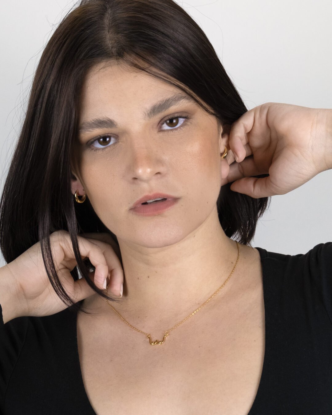 Woman wearing casual look complimented with the Two of a Kind Necklace, in sterling silver and gold plated, and the Simple Huggie Earrings