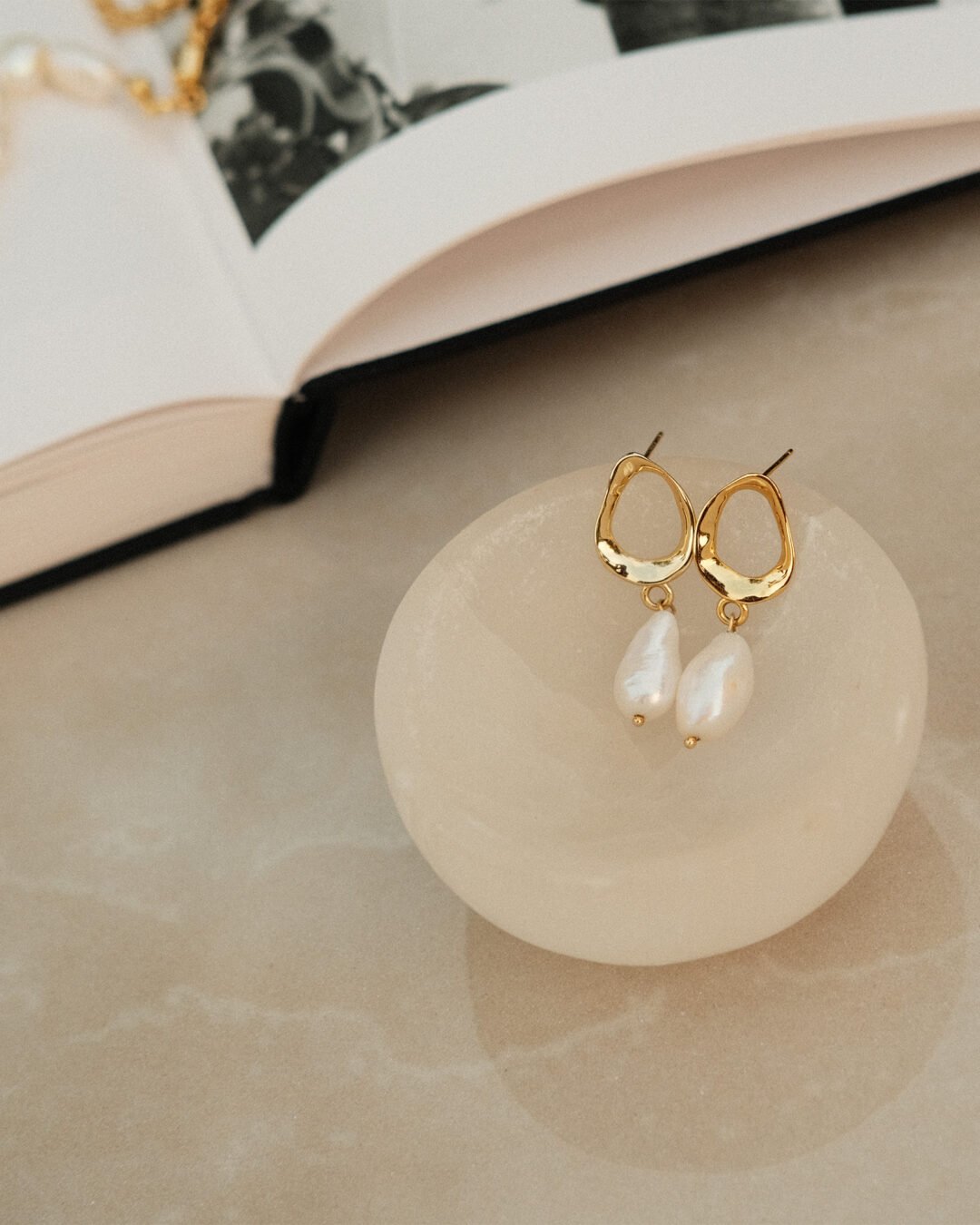 pearl drop earrings gold plated on a small glass tray to showcase it shine and beauty